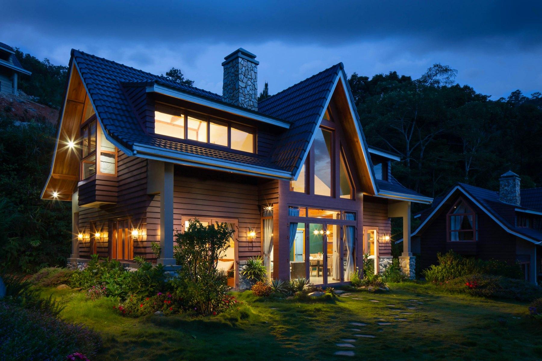 Craftsman home with lit windows at dusk surrounded by trees